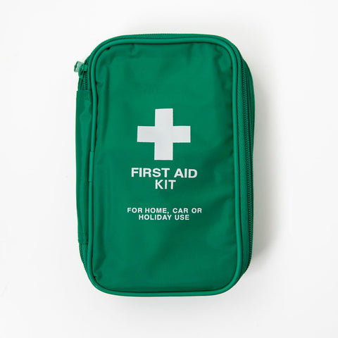 A green first aid kit with a white cross on the front, labeled 'FIRST AID KIT FOR HOME, CAR OR HOLIDAY USE'.